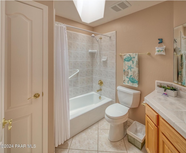 full bathroom featuring vanity, shower / bath combination with curtain, a skylight, tile patterned flooring, and toilet