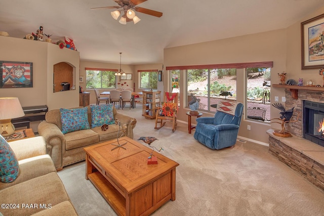 carpeted living room with a fireplace and ceiling fan with notable chandelier