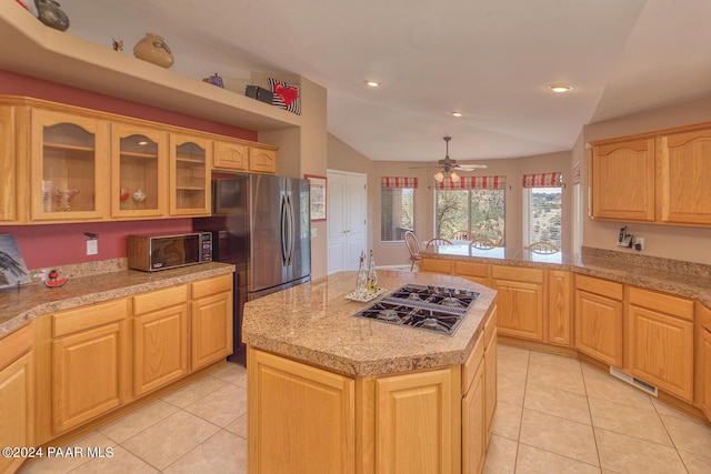 kitchen featuring a center island, light brown cabinets, lofted ceiling, and stainless steel gas cooktop