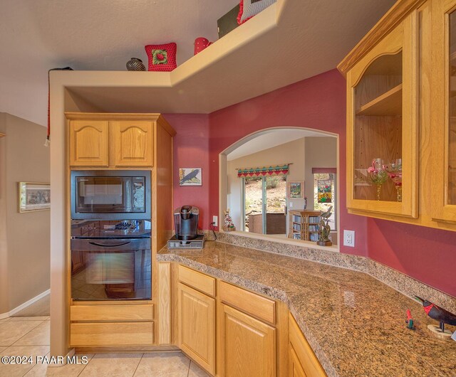 kitchen with black appliances, light tile patterned floors, a textured ceiling, and light brown cabinetry