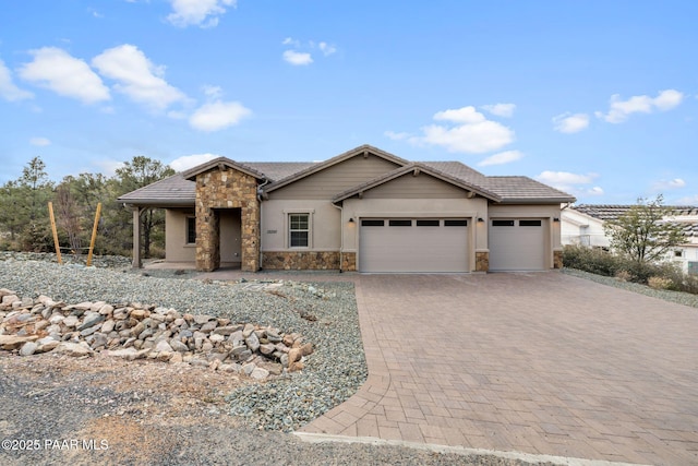 view of front of property with a tile roof, decorative driveway, stone siding, and an attached garage