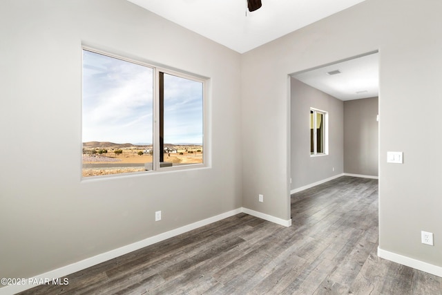 spare room with a ceiling fan, visible vents, baseboards, and wood finished floors