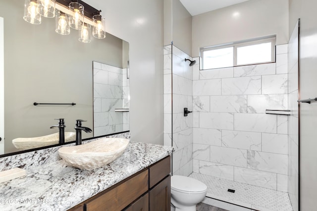 bathroom featuring vanity, toilet, and a tile shower