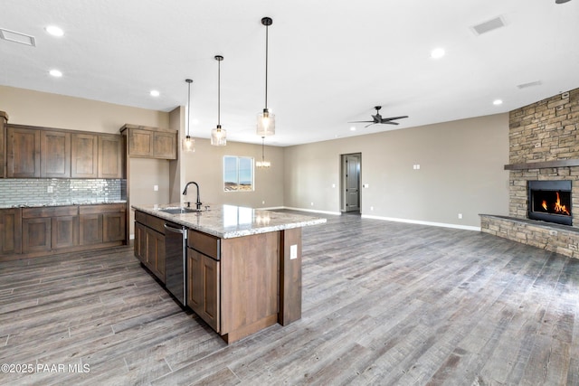 kitchen with visible vents, decorative backsplash, open floor plan, a fireplace, and a sink