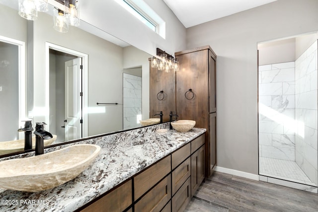 bathroom featuring double vanity, wood finished floors, a sink, and baseboards