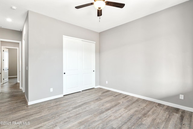 unfurnished bedroom with a ceiling fan, a closet, baseboards, and wood finished floors