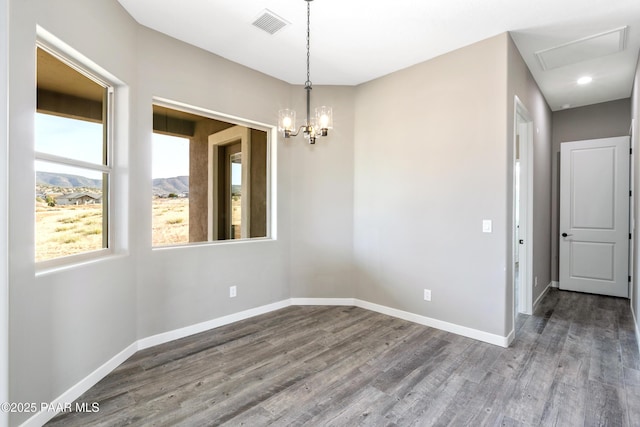 spare room with a notable chandelier, wood finished floors, visible vents, and baseboards