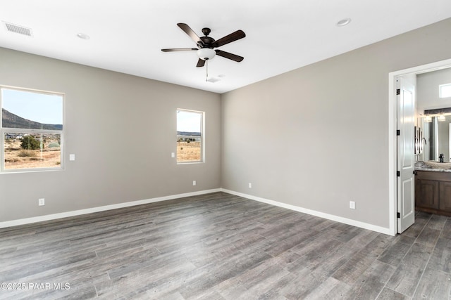 unfurnished bedroom featuring wood finished floors, visible vents, and multiple windows