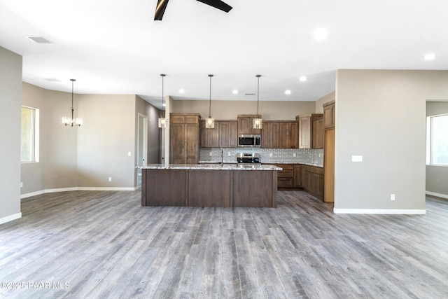 kitchen featuring pendant lighting, stainless steel appliances, light stone counters, and tasteful backsplash