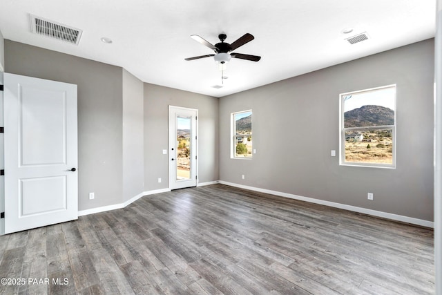 spare room featuring baseboards, visible vents, ceiling fan, and wood finished floors