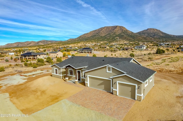 view of front of home with decorative driveway, stone siding, a mountain view, and stucco siding