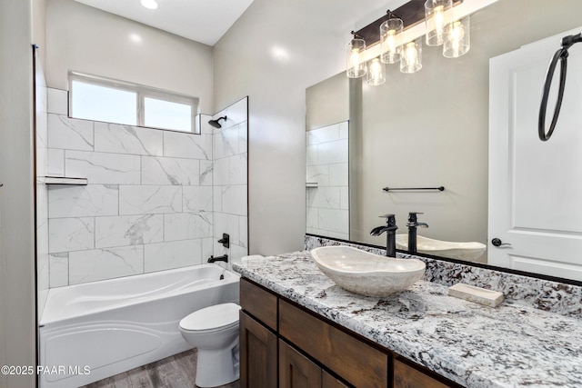 full bathroom with vanity, tiled shower / bath combo, hardwood / wood-style flooring, and toilet