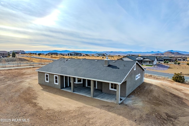 view of front of home featuring roof with shingles, a mountain view, and stucco siding