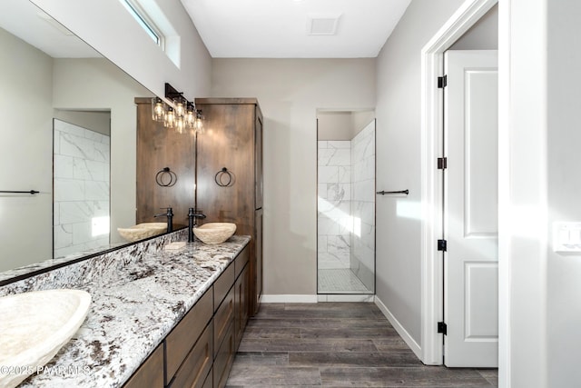 bathroom featuring double vanity, wood finished floors, a sink, and a shower stall