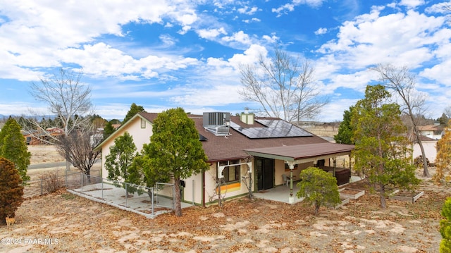 rear view of property with solar panels, a patio, and central AC