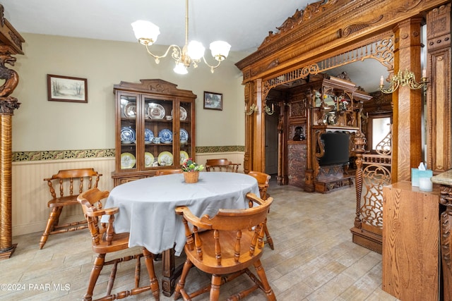 dining room featuring a notable chandelier, wood walls, and light wood-type flooring