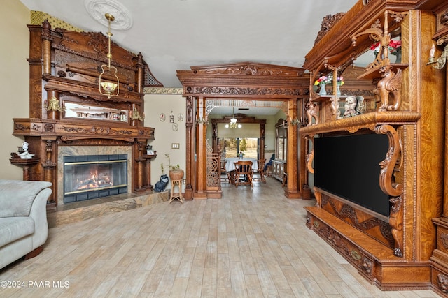 living room with a notable chandelier, light hardwood / wood-style floors, lofted ceiling, and a premium fireplace