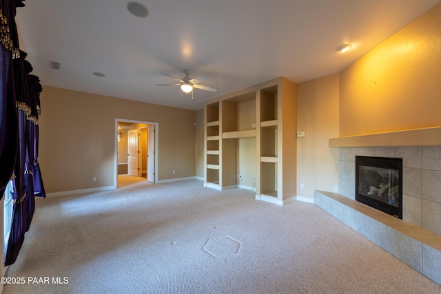 unfurnished living room featuring ceiling fan, a tiled fireplace, carpet floors, and baseboards