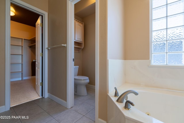 full bath featuring a whirlpool tub, toilet, baseboards, tile patterned flooring, and a spacious closet