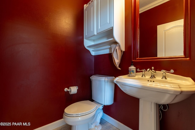 bathroom with baseboards, tile patterned floors, and toilet
