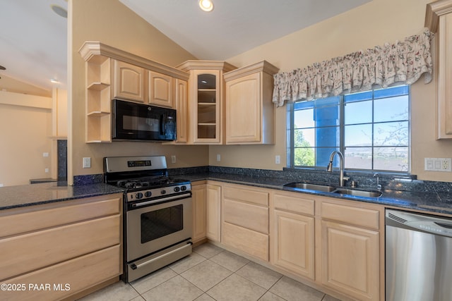 kitchen featuring light brown cabinetry, dark stone countertops, stainless steel appliances, and lofted ceiling