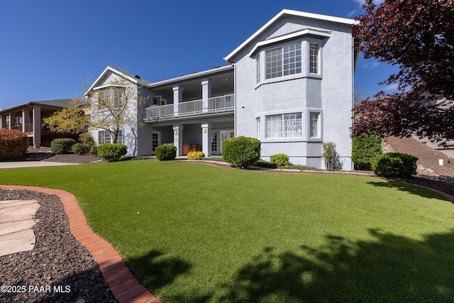 exterior space featuring stucco siding, a yard, and a balcony