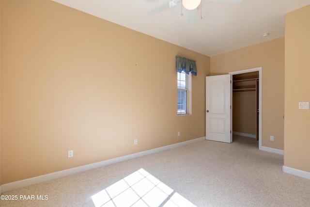 unfurnished bedroom featuring a ceiling fan, baseboards, light carpet, and a spacious closet