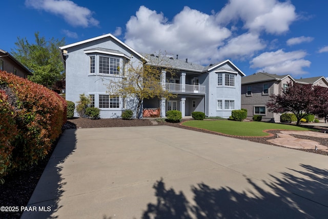 view of front of house with a front lawn, a balcony, and stucco siding