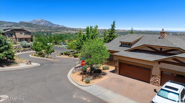 532 Goshawk Trl, Prescott, AZ 86301 - view of front of house featuring roof with shingles, stone siding, a garage, a mountain view, and decorative driveway
