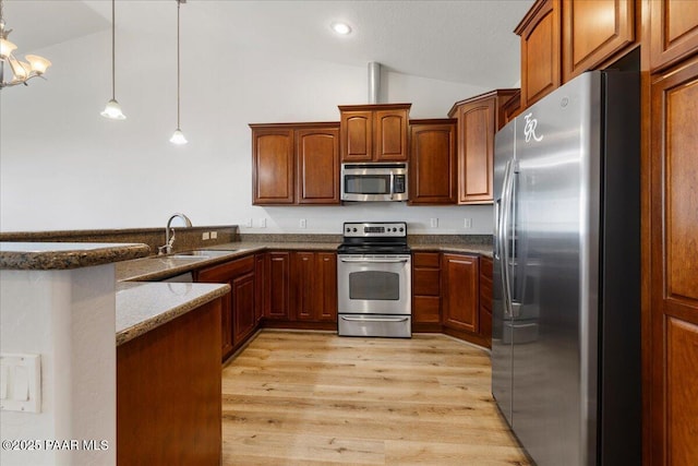 532 Goshawk Trl, Prescott, AZ 86301 - kitchen with stainless steel appliances, lofted ceiling, dark stone countertops, a peninsula, and light wood finished floors