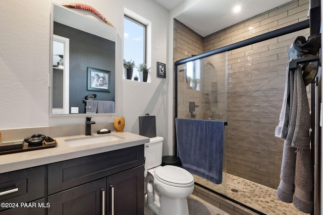 bathroom with vanity, toilet, and a shower with door