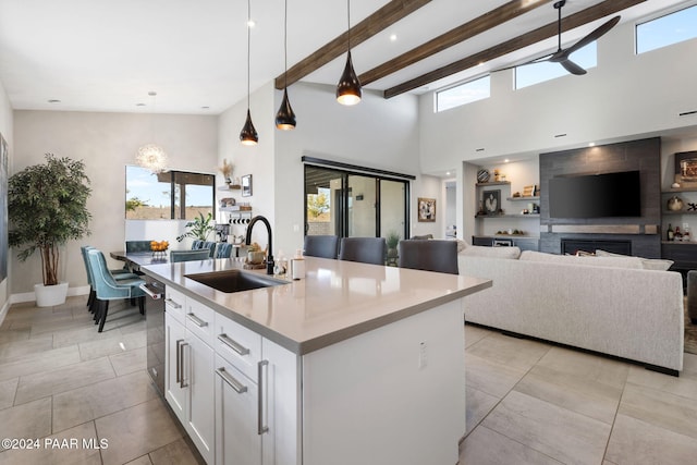 kitchen with ceiling fan, sink, decorative light fixtures, a center island with sink, and white cabinets