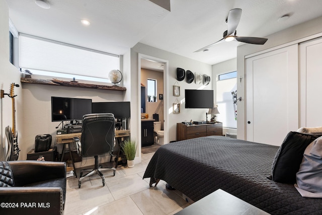 tiled bedroom featuring ceiling fan and connected bathroom