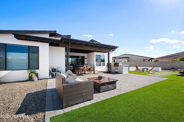 back of house featuring an outdoor kitchen, a patio, and an outdoor hangout area