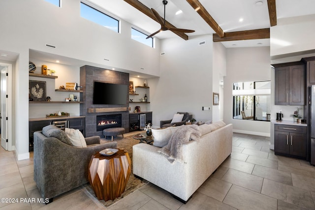 tiled living room with beamed ceiling, a healthy amount of sunlight, a tile fireplace, and a high ceiling