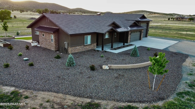 9192 N Doc Bar Rd, Prescott Valley, AZ 86315 - view of front of property with stone siding, driveway, a mountain view, an attached garage, and a standing seam roof