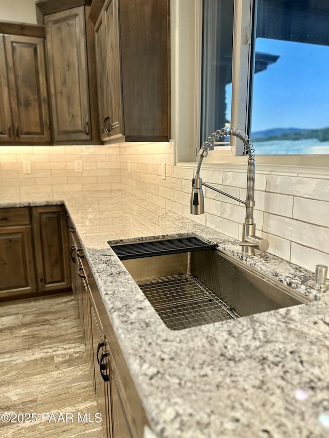 9192 N Doc Bar Rd, Prescott Valley, AZ 86315 - kitchen featuring a sink, decorative backsplash, light stone countertops, and dark brown cabinets
