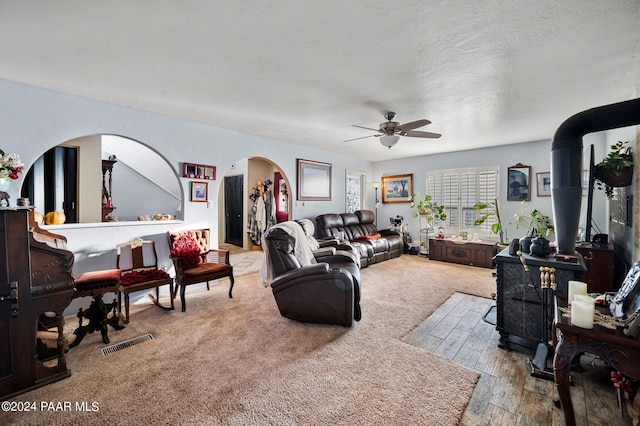 carpeted living room featuring ceiling fan and a textured ceiling