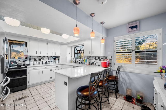 kitchen with kitchen peninsula, tasteful backsplash, white cabinets, and stainless steel appliances