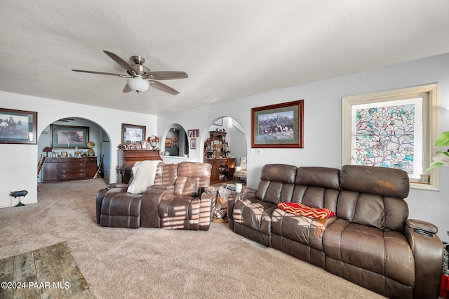 carpeted living room featuring ceiling fan and a textured ceiling