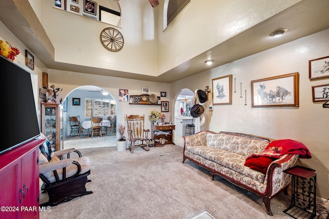 carpeted living room featuring ceiling fan, a healthy amount of sunlight, and a towering ceiling