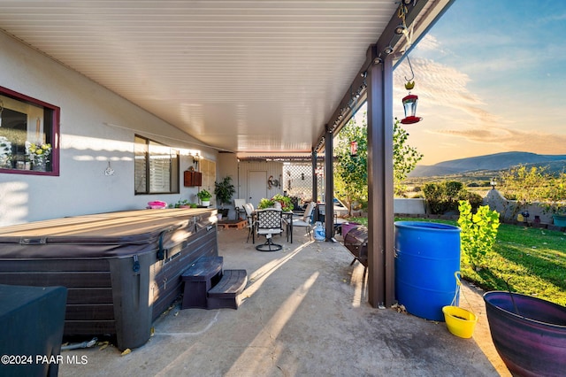 patio terrace at dusk with a mountain view and a hot tub