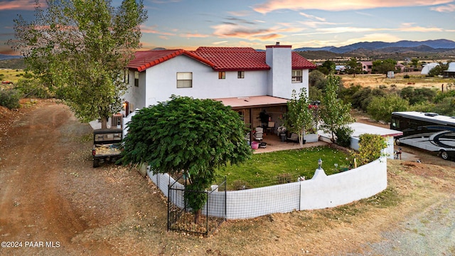 view of front of home with a mountain view, a patio area, and a lawn