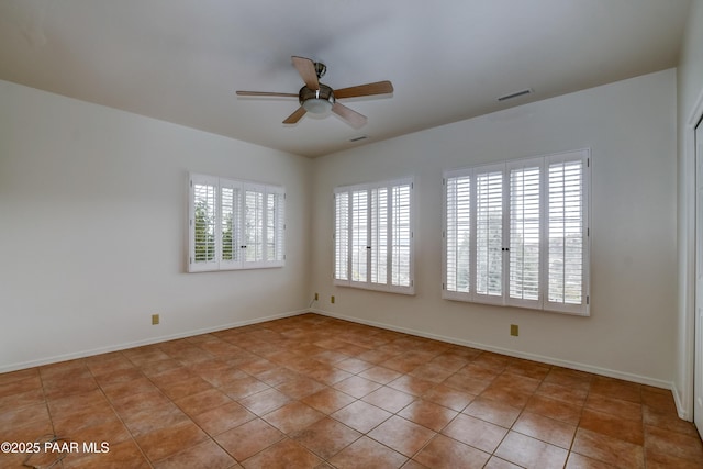 spare room featuring light tile patterned flooring, visible vents, baseboards, and a ceiling fan