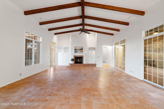 unfurnished living room featuring a glass covered fireplace, beam ceiling, a ceiling fan, and high vaulted ceiling