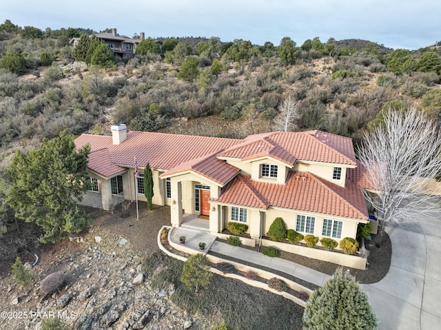 view of front of home featuring stucco siding, a chimney, and a tile roof