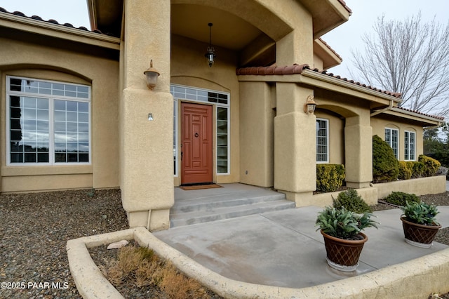 doorway to property with a tile roof and stucco siding