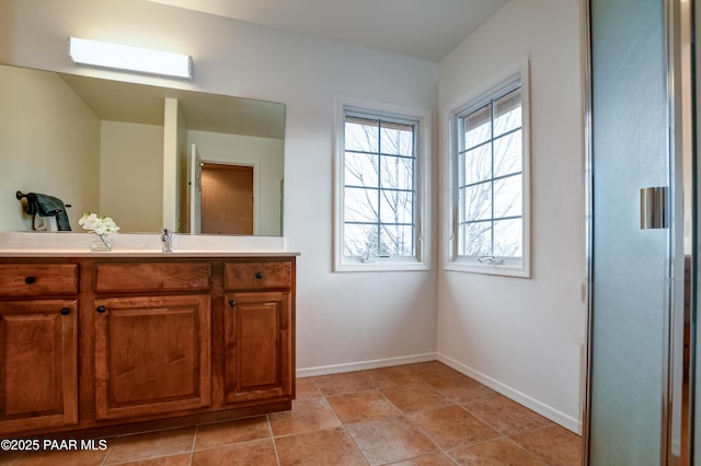 bathroom with tile patterned flooring, a skylight, vanity, and baseboards