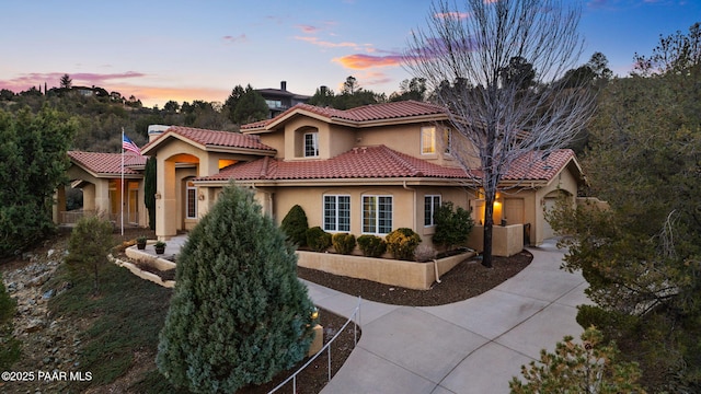 mediterranean / spanish-style house featuring stucco siding, concrete driveway, and a tiled roof