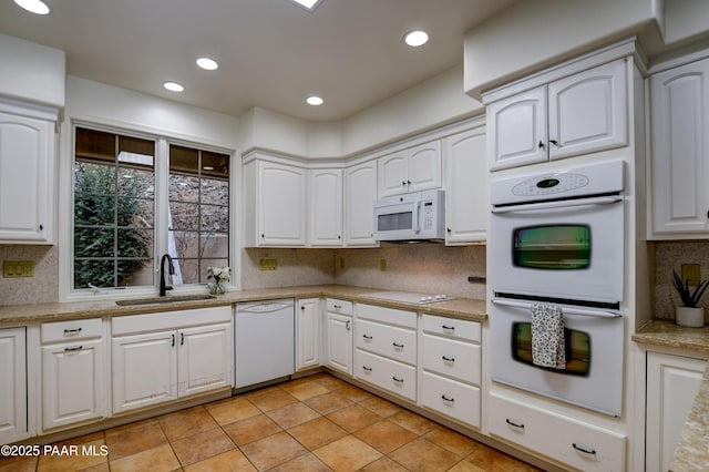 kitchen featuring tasteful backsplash, recessed lighting, white cabinets, white appliances, and a sink